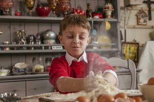 weinig jongen hebben pret en bereiden de deeg voor koekjes foto