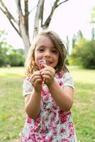 portret van schattig meisje is tonen een haar- klem in een openbaar park foto