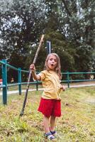 glimlachen weinig meisje spelen met een stok door een vijver in een openbaar park foto