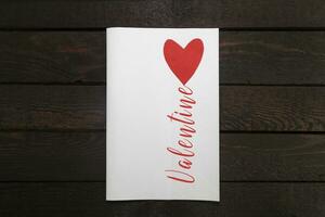 valentijnsdag kaart. wit papier kaart met rood hart en opschrift valentijn. foto