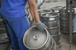 Mens zetten bier vaatjes Aan de productie lijn in de fabriek foto