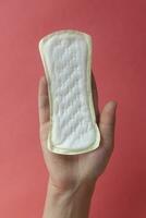 vrouw handen Holding een vrouwelijk hygiëne kussen. handen van vrouw houden menstruatie- stootkussens of sanitair servetten voor Dames foto