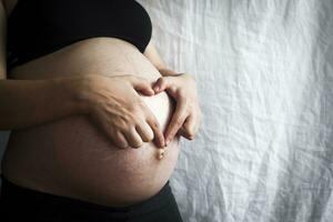 zwanger vrouw Bij 9e maand tonen hart met handen foto