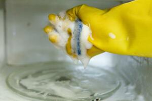 vrouw handen in rubber handschoenen het wassen magnetronoven foto