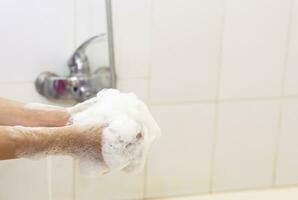 vrouw het wassen handen met een spons in de badkamer. vrouw het wassen armen met een schuimend spons in de bad. lichaam zorg en schoon concept foto