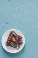 dun pannekoeken met aardbeien en chocola room. pannekoeken met vers aardbeien Aan helder blauw tafel foto