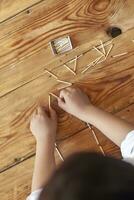 een jongen spelen met lucifers. jong kind Toneelstukken bij elkaar passen stokjes Aan houten achtergrond. foto