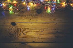 Kerstmis decoratief lichten. Kerstmis slinger lichten Aan hout. kleurrijk Kerstmis licht bollen Aan rustiek bruin plank foto