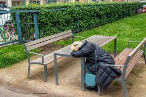 Wenen, Oostenrijk - 05.13.2023 moe vrouw slaapt zittend Bij een tafel in een van de parken in Wenen. foto