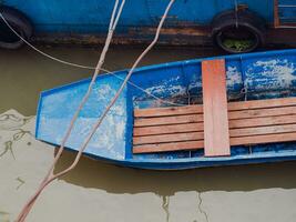 oud blauw metaal boot aangemeerd drijvend Aan vervuild rivier- foto