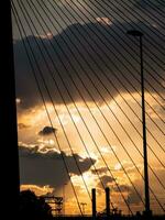 snelweg, lantaarnpaal, schoorsteen brug silhouetten Bij zonsondergang foto