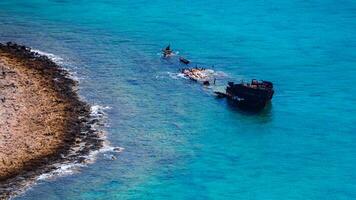 gezonken schip in de buurt de rotsachtig kust - mooi tropisch blauw water foto