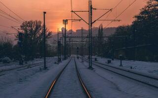 sneeuw gedekt leeg trein sporen Bij zonsondergang foto