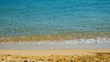 zanderig strand met klein golven - blauw zee en geel zand foto