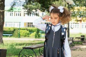 meisje met een rugzak in de buurt de school- na klassen, ongelukkig, moe en hoofdpijn. de kind is huilen, Holding zijn hoofd in zijn handen. academisch mislukkingen, arm cijfers, overwerk foto