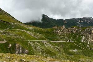 tunnel Ingang in de midden- van groen bergen gedekt met wit wolken foto