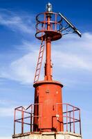 een rood vuurtoren met een zonne- paneel Aan top foto