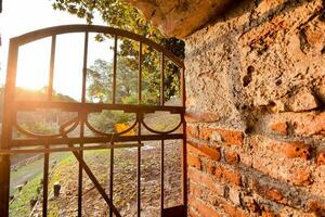 de zon is instelling achter een steen muur en poort foto