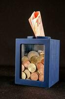 een blauw doos met munten en geld binnen foto
