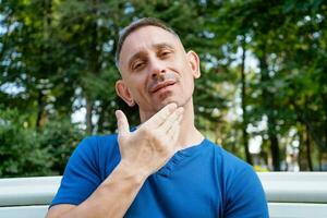 knap portret van een Mens in een blauw t-shirt zittend Aan een park bank foto