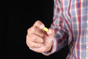jonge man hand met medische pillen geïsoleerd op zwart foto