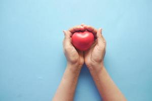 vrouwen die rood hart op blauwe achtergrond houden foto