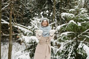 schattig meisje gooit sneeuw Aan de straat foto