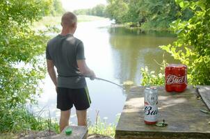 budweiser knop bier blikjes pak Aan oud tafel en visser Bij rivier- Aan achtergrond foto