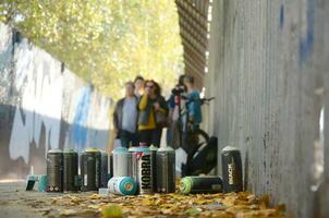 Charkov, Oekraïne - oktober 19, 2019 gebruikt verstuiven blikjes voor graffiti schilderij door veel verf merken buitenshuis in herfst doorbladert en artiest in schilderij werkwijze foto