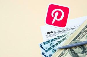 pinterest gedrukt logo leugens met 1040 individu inkomen belasting terugkeer het formulier met terugbetaling controleren en honderd dollar rekeningen Aan beige achtergrond. helpen in belasting periode van sociaal netwerk concept foto