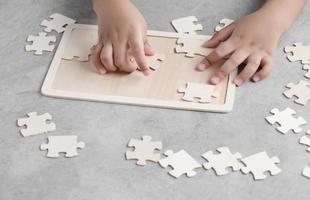 Aziatische kleine jongen die houten puzzel speelt foto