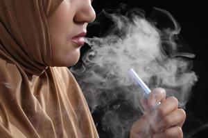 close-up jonge moslimvrouw die e-sigaret rookt op zwarte achtergrond