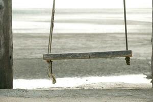 houten schommel hangende van de bar met strand achtergrond foto