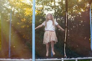 weinig kind meisje jumping Aan de trampoline in de terug werf foto