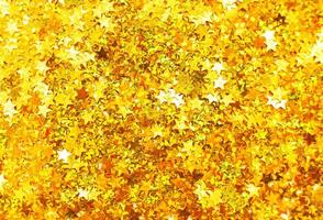 glinsterende achtergrond van gouden pailletten in het formulier van sterren detailopname. fonkeling feestelijk textuur. foto