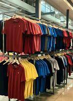 rij van modieus polo t-shirts voor Mens Aan houten hanger of rek in een kleding winkel kleinhandel winkel concept door ai gegenereerd foto