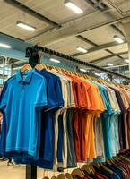 rij van modieus polo t-shirts voor Mens Aan houten hanger of rek in een kleding winkel kleinhandel winkel concept door ai gegenereerd foto