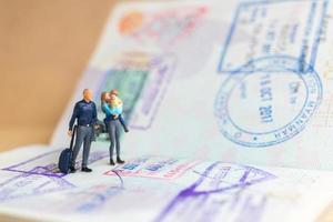 miniatuur mensen paar staande op paspoort met immigratie gestempeld foto