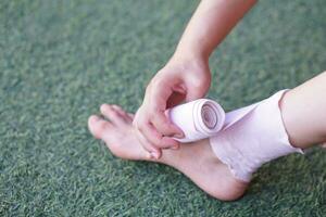 dichtbij omhoog hand- is omhulsel verband Aan verstuikt enkel. concept, eerste hulp, Gezondheid zorg. inpakken elastisch verband in de omgeving van verstuikt enkel naar Verlichting zwelling of pijn. ongeluk blessure. foto