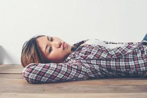 eenzame trieste vrouw diep in gedachten vast op houten vloer. foto