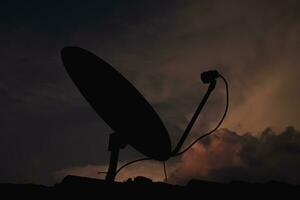 silhouet van satelliet schotel Aan zonsondergang lucht. foto