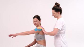 therapeut past kinesiotape toe op het vrouwelijk lichaam. fysiotherapie en kinesiologie concepten.