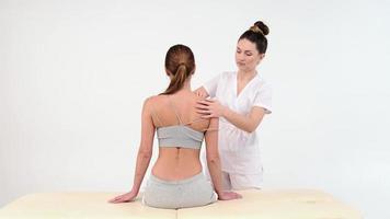 fysiotherapeut die de schouder van een vrouwelijke patiënt masseert. over de schouder weergave van masseur die diepe weefselmassage uitvoert. 4k beeldmateriaal. close-up filmpje. foto