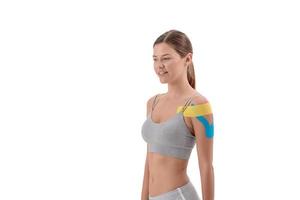 gekleurde kinesiotherapie tape op jonge sportvrouw schouder geïsoleerd op een witte achtergrond. kopieer ruimte
