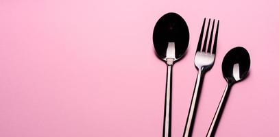 metalen lepel en vork geïsoleerd op roze achtergrond foto