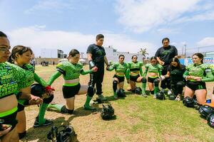 puebla, Mexico 2023 - Mexicaans Dames Amerikaans Amerikaans voetbal spelers verzameld in een cirkel luisteren naar de van de coach instructies foto