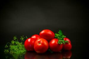 rijp rood tomaten met Groenen Aan zwart achtergrond. foto