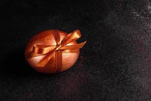 paasei met cadeautape op een donkere houten ondergrond foto