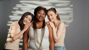 gezond gloeiend Dames bevorderen zelf vertrouwen in studio, hebben stralend natuurlijk huid poseren Aan camera. jong verschillend modellen omarmen onvolkomenheden in nieuw huidsverzorging campagne. foto