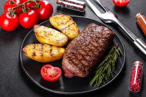 ribeye steak met aardappelen, uien en cherrytomaatjes foto